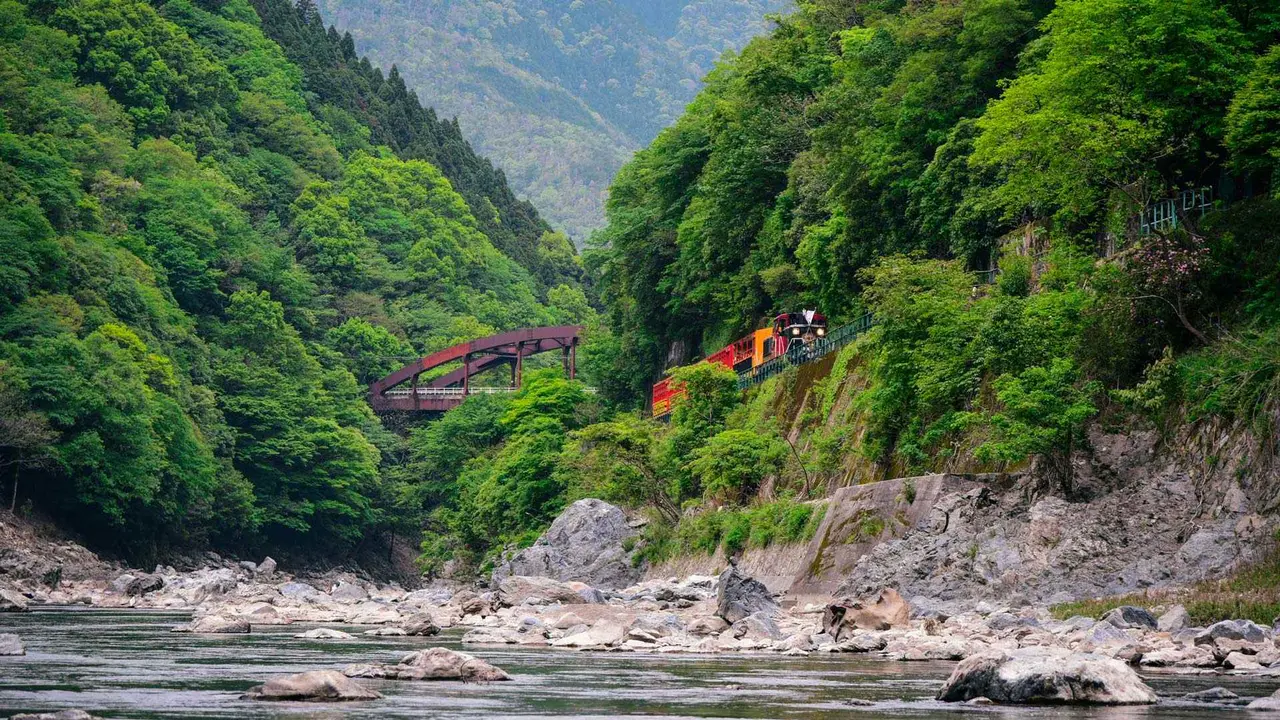 A train running along Hozugawa River in Arashiyama, Kyoto, Japan