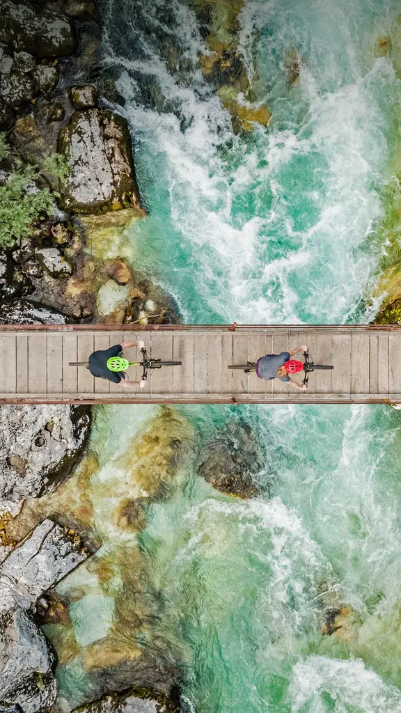 斯洛文尼亚索奇河上的木制吊桥上骑自行车的人的鸟瞰图